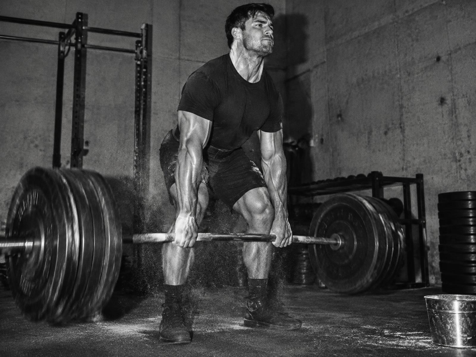 Man pulling a heavy barbell deadlift in a concrete gym